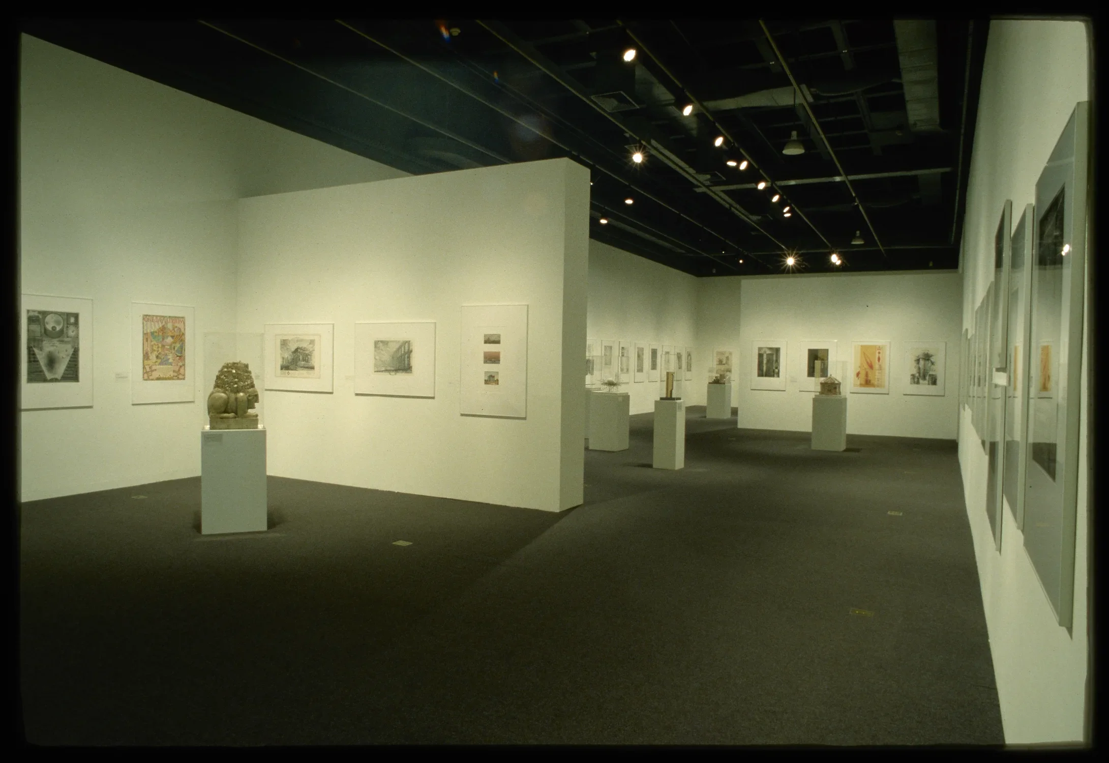 Architectural illustrations line the gallery walls. Models made from various materials sit on glass covered pedestals.