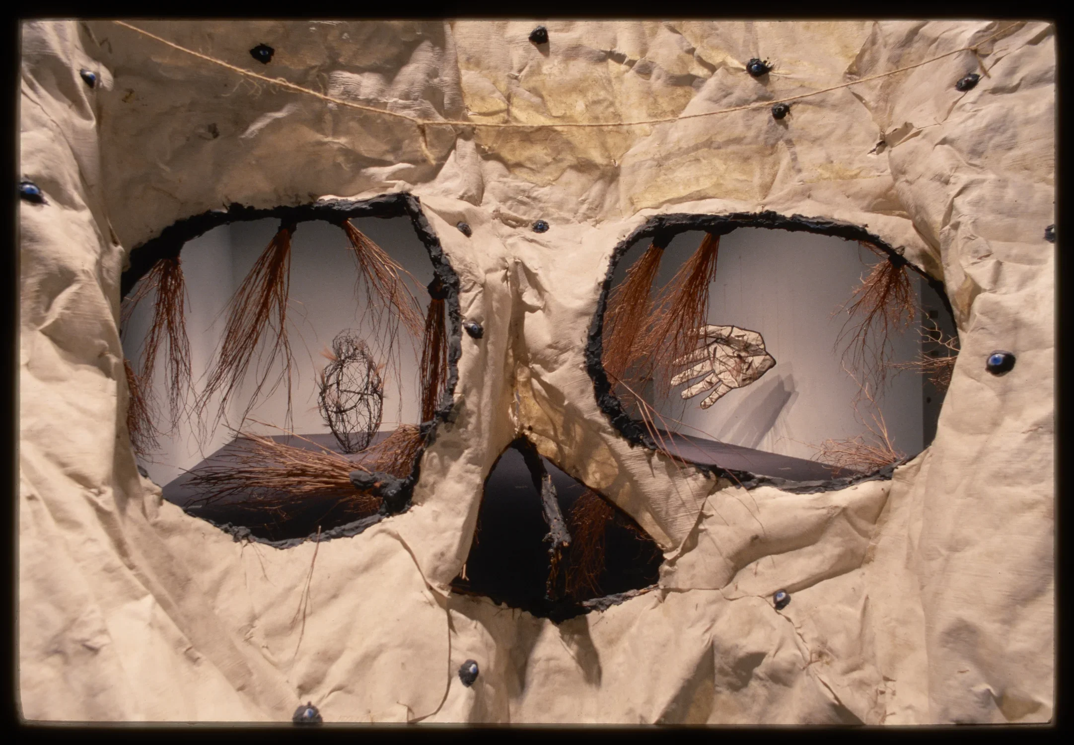 The eyes and nose of a skull show the installation of a heart and hand sculpture at the other end of the gallery.