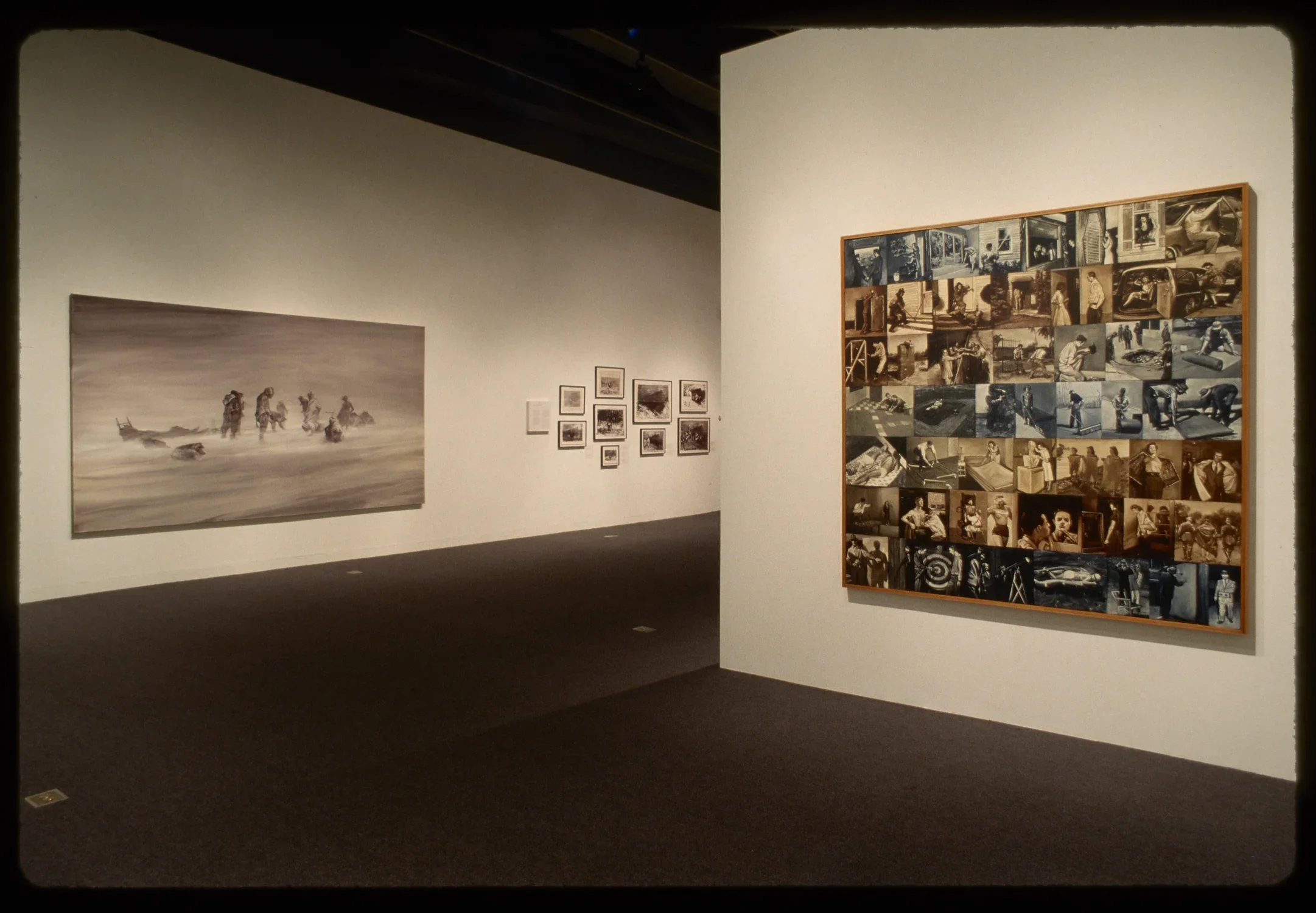 Large black and white oil painting of desert nomads and ten framed photos hang on adjacent wall to patchwork of sepia photos.