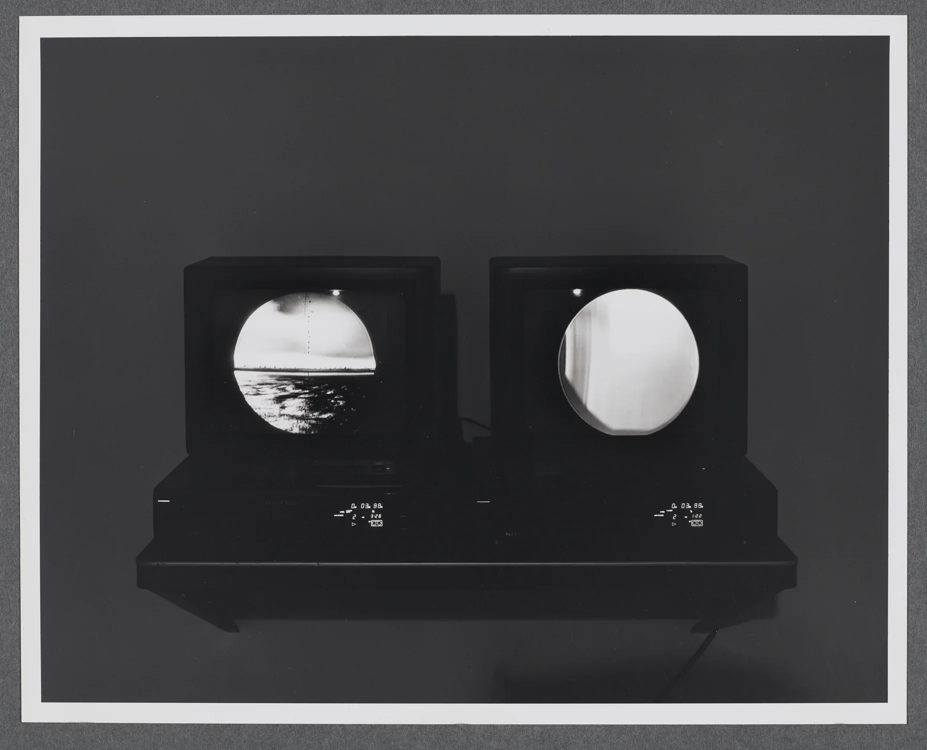 Two monitors sit side by side on a shelf. Each shows images within circular frames as if looking through binoculars.  