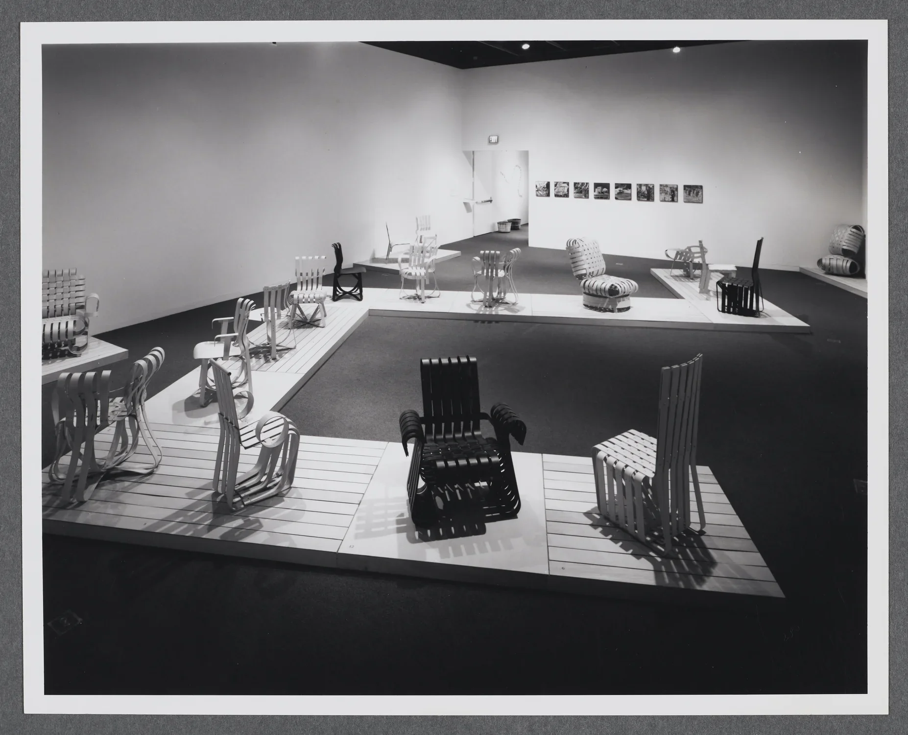 Bentwood chairs are arranged upon a wooden platform that makes its way through the gallery space. 