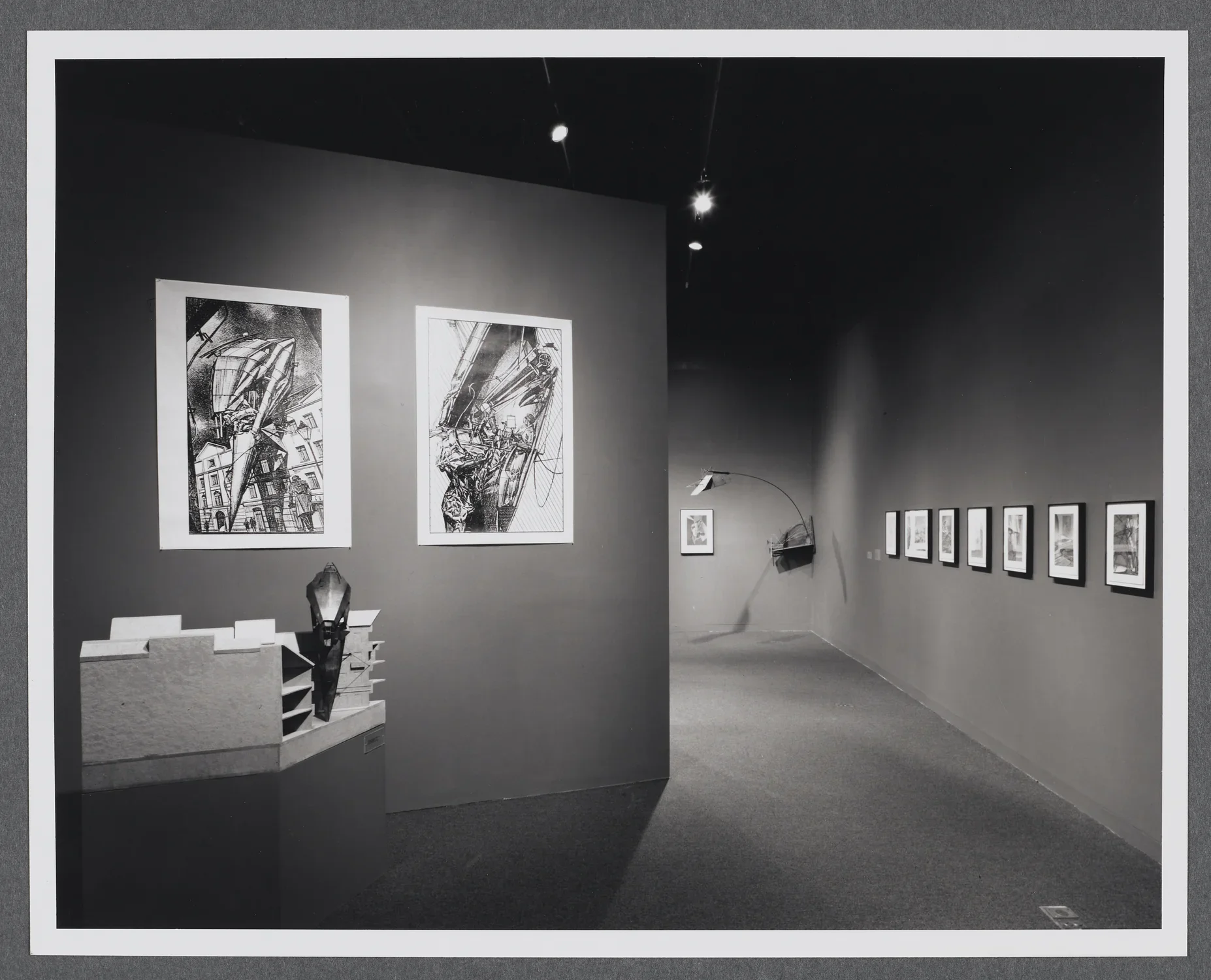 3D models sit on pedestals around the gallery. Large scale drawings hang on the gallery walls alongside the models. 