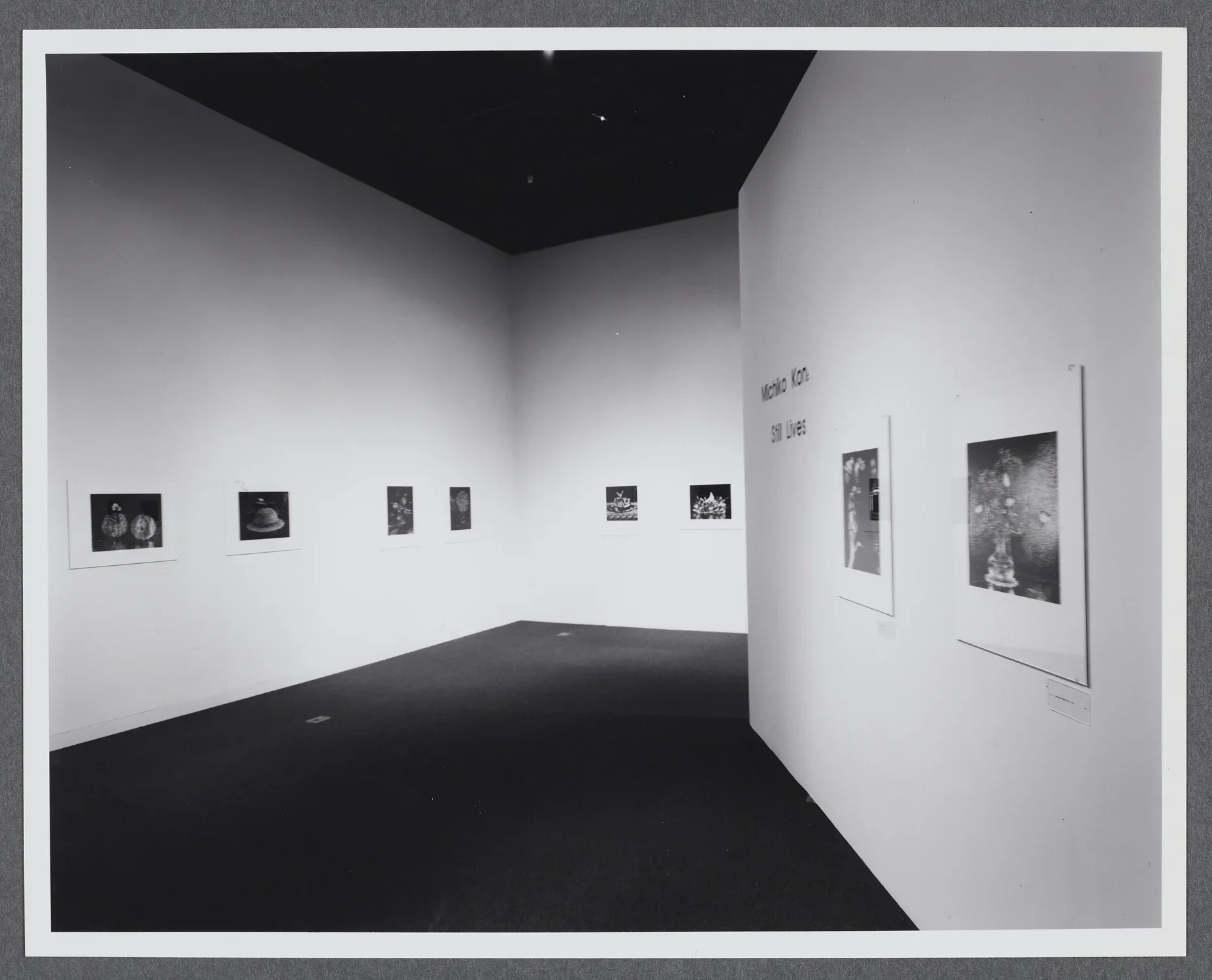 Black and white photographs line the gallery walls. They are all displayed in a row at the same height. 
