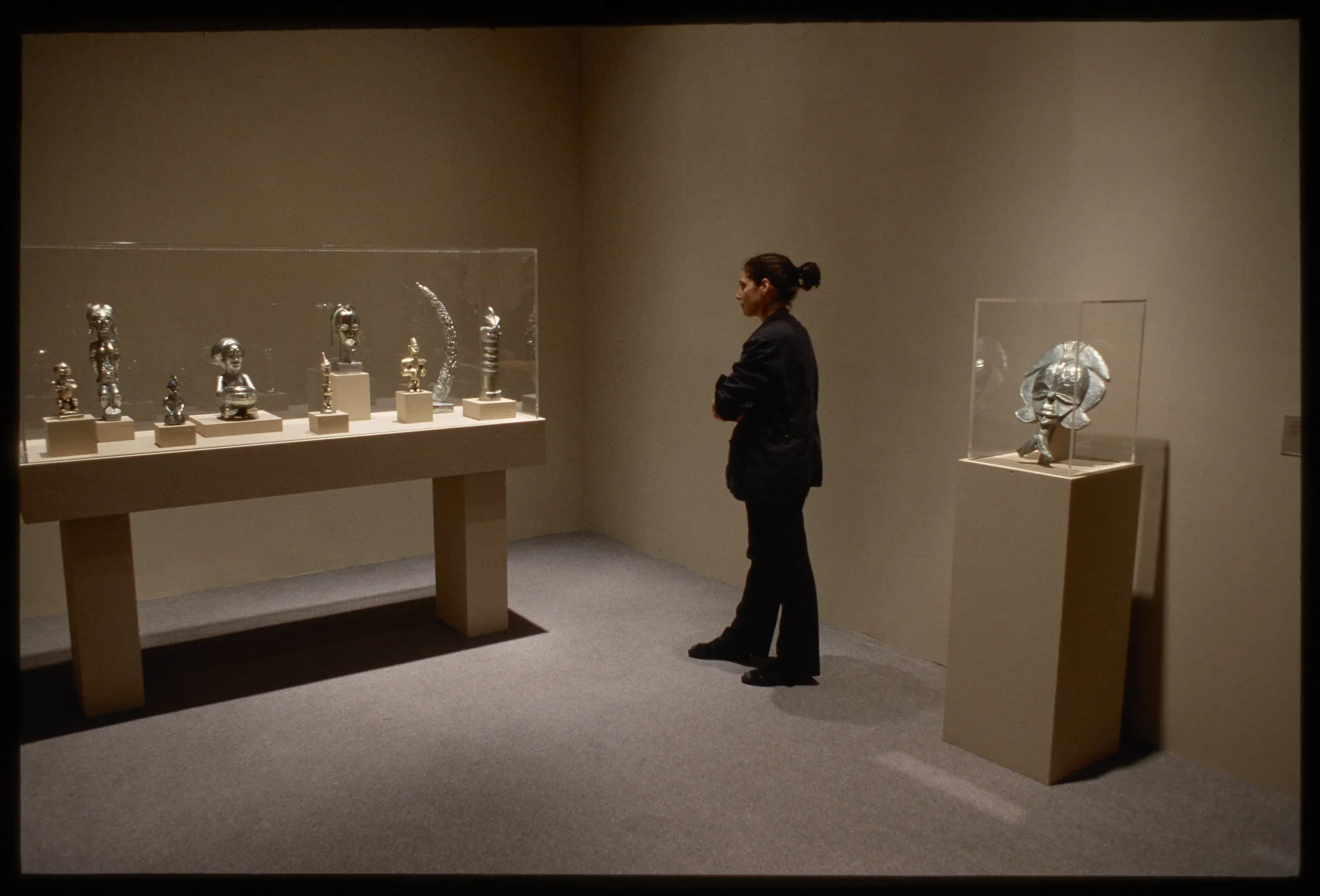 Viewer looking at vitrine with small tropy like sculptures. 