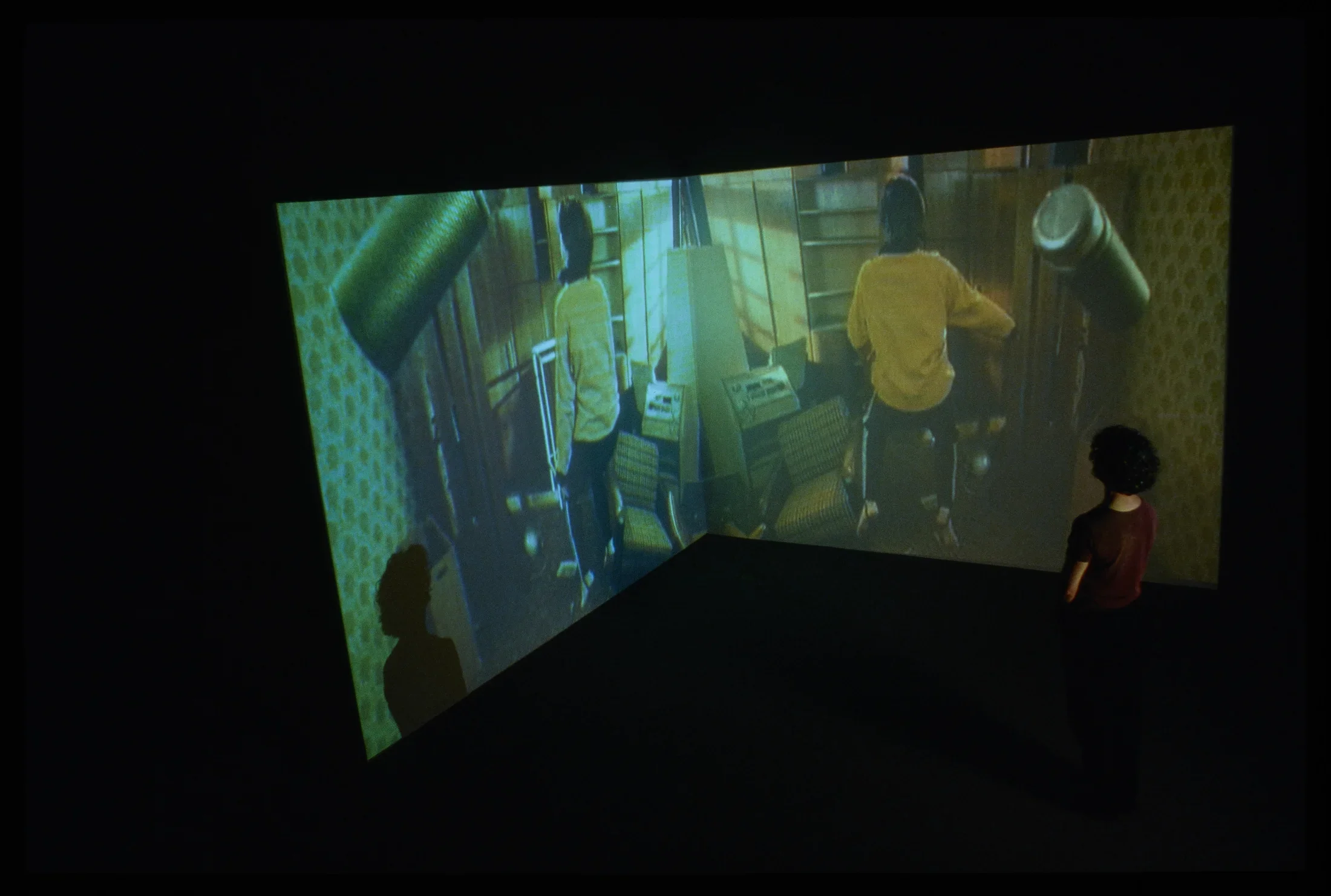 In a dark gallery, 2 screens in a corner.