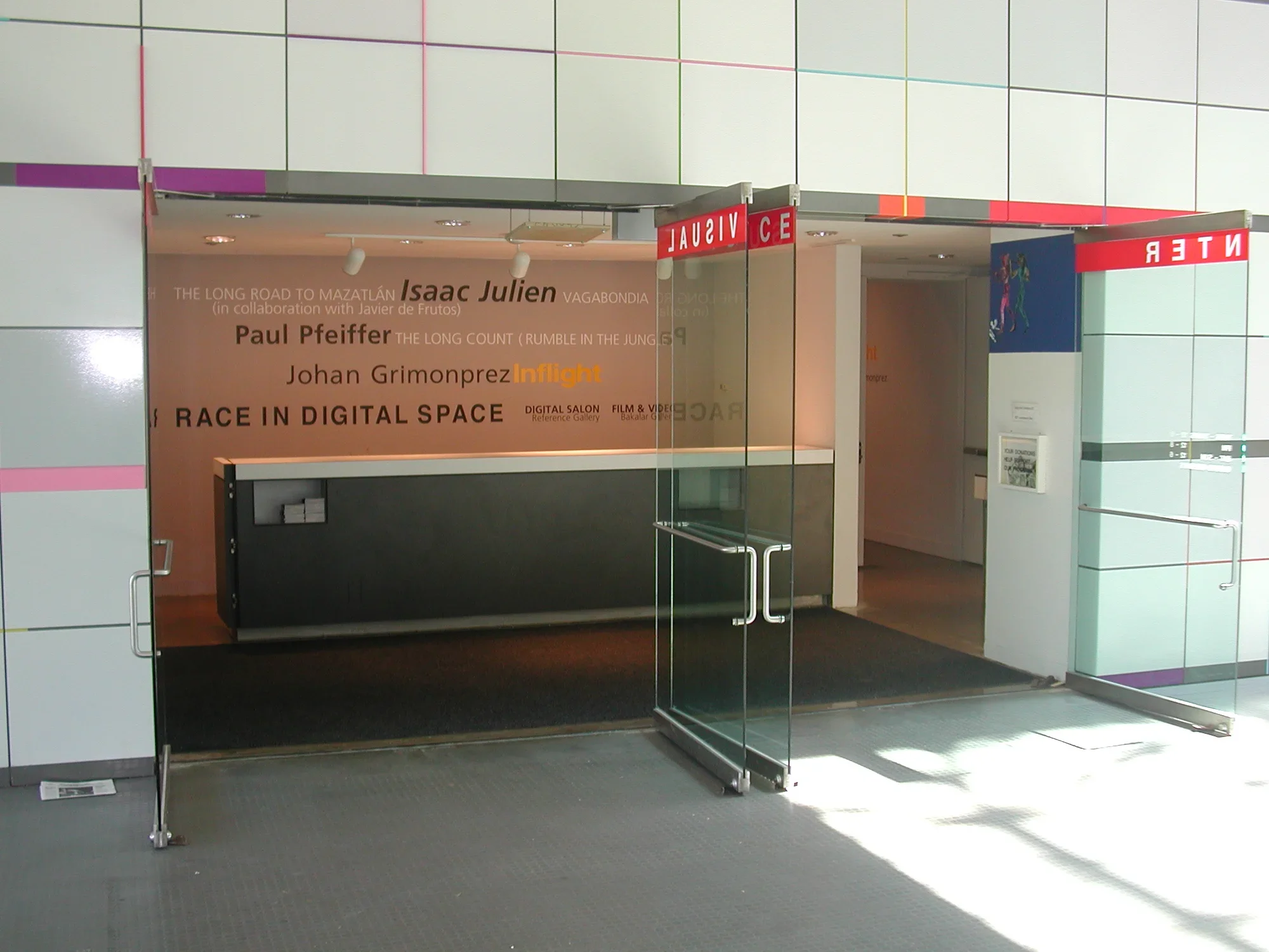 Entrance of the List gallery, glass doors open onto the wall listing the current artist shows.