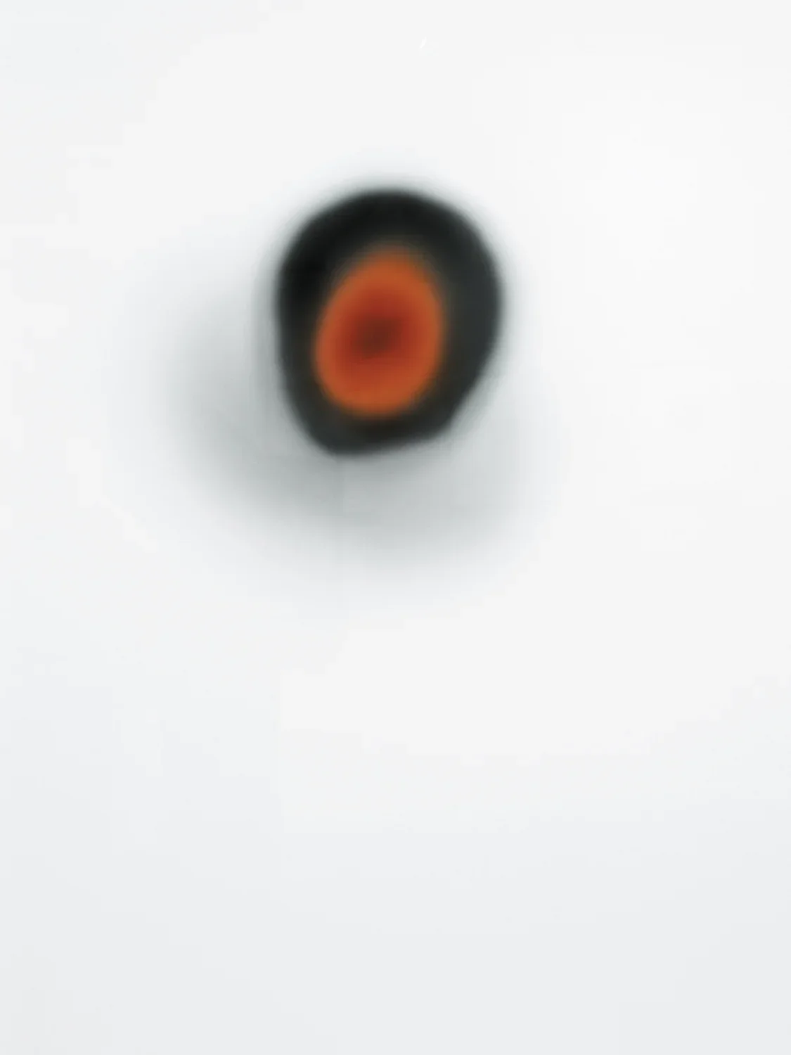 Blurred black spot with red interior, and a silver haze around the edges.