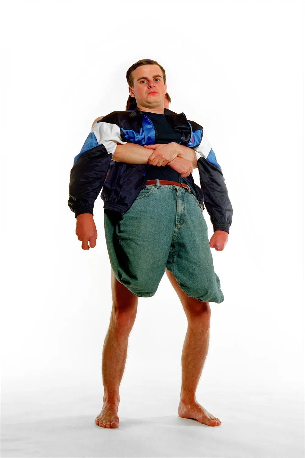 Able bodied man hugs arms around a man without legs, holding him up from behind