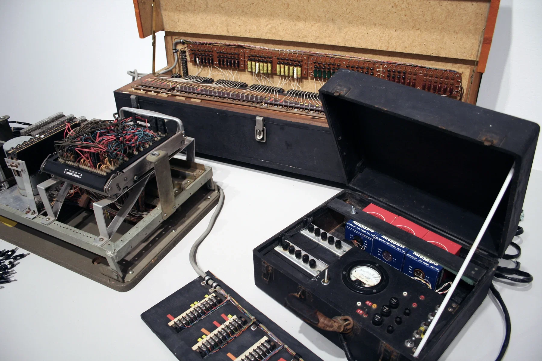 Close up photo of several vintage electronic objects displayed on a white pedestal.