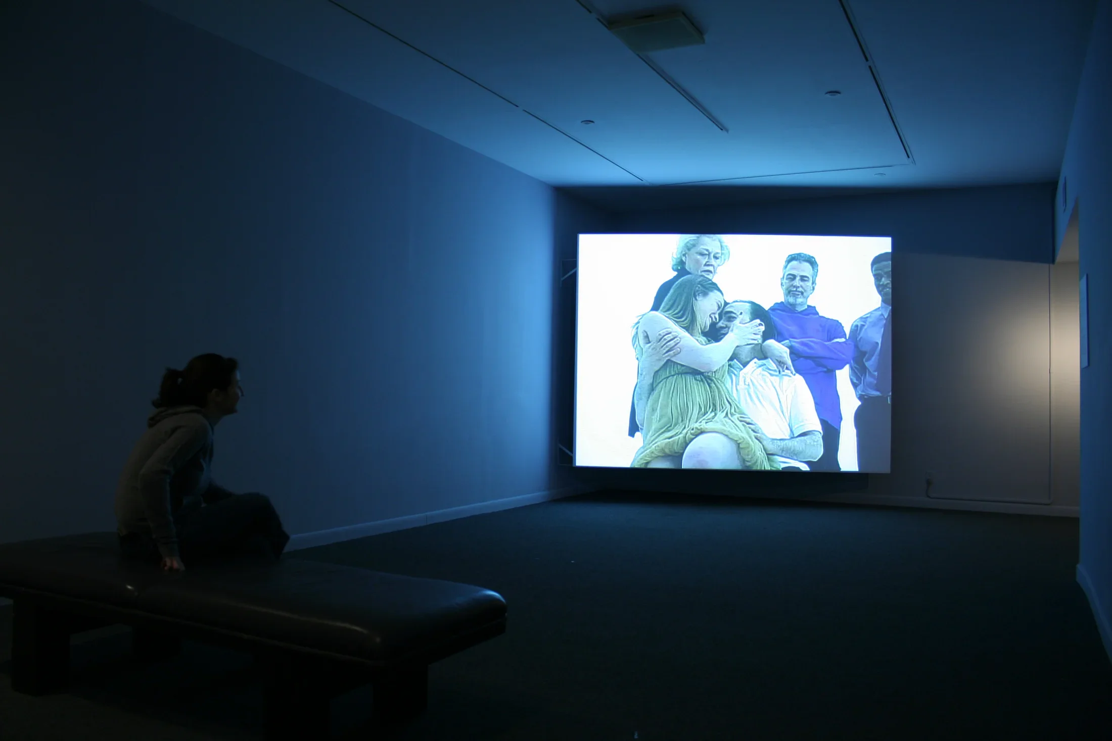 1 viewer looking at a large screen with 5 people watching 