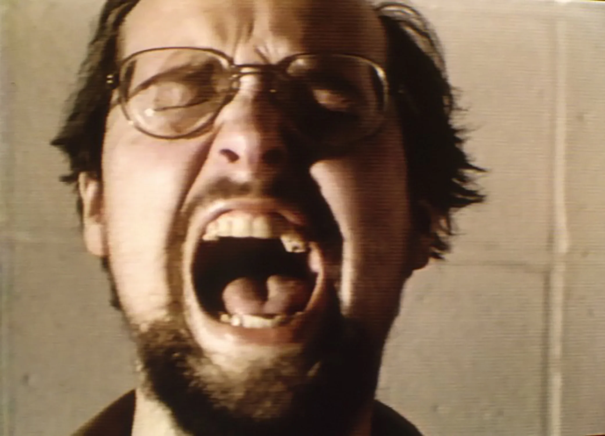 Video still of man yelling with mouth open and eyes closed.