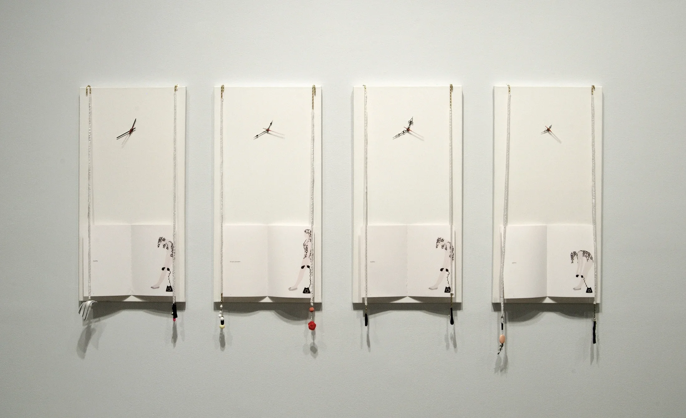 Four white panels hang against the wall. At the bottom, an open book with an illustration of a woman slumped over.