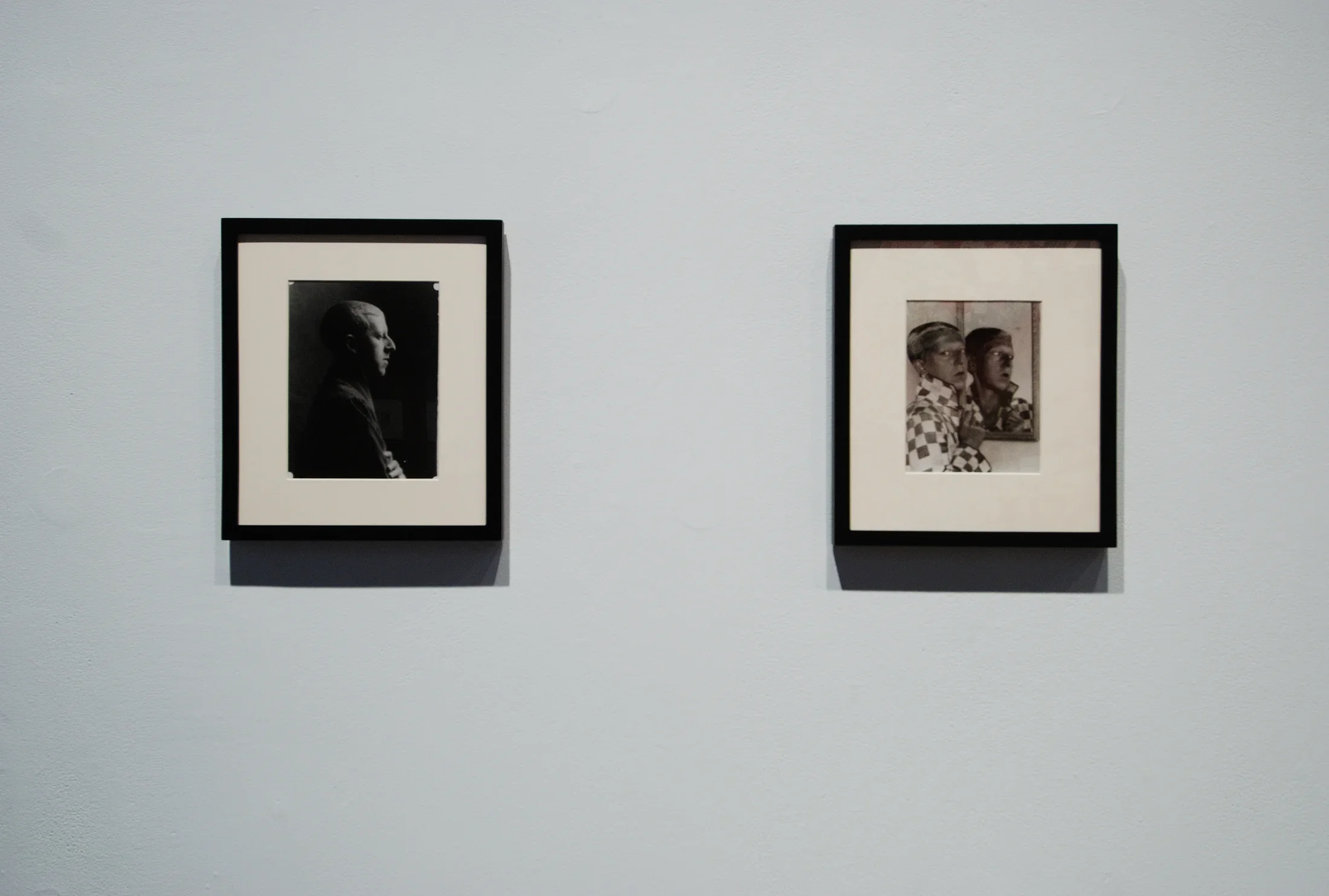 Two black and white photos, a dimly lit side profile portrait and a person posing in a checkered jacket in front of a mirror.