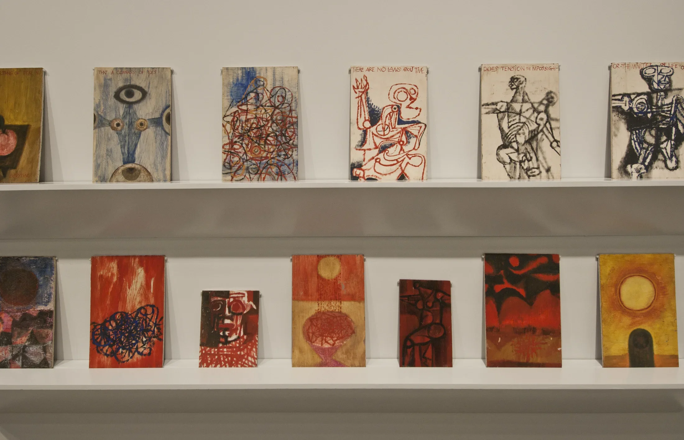 2 rows of 6 paintings leaning against a shelf.