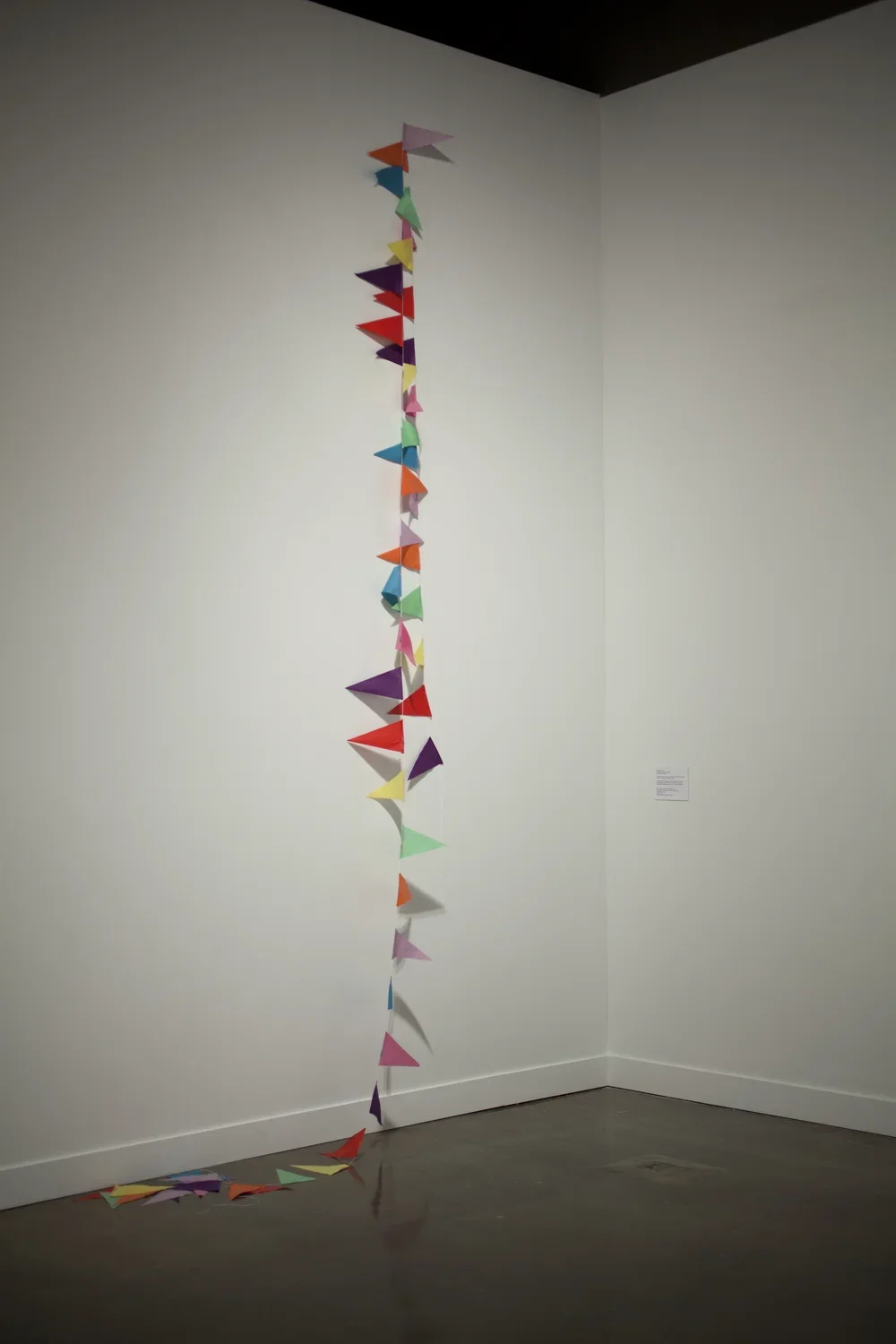 A colorful string of banners hangs down from top of a wall and drapes onto the floor.