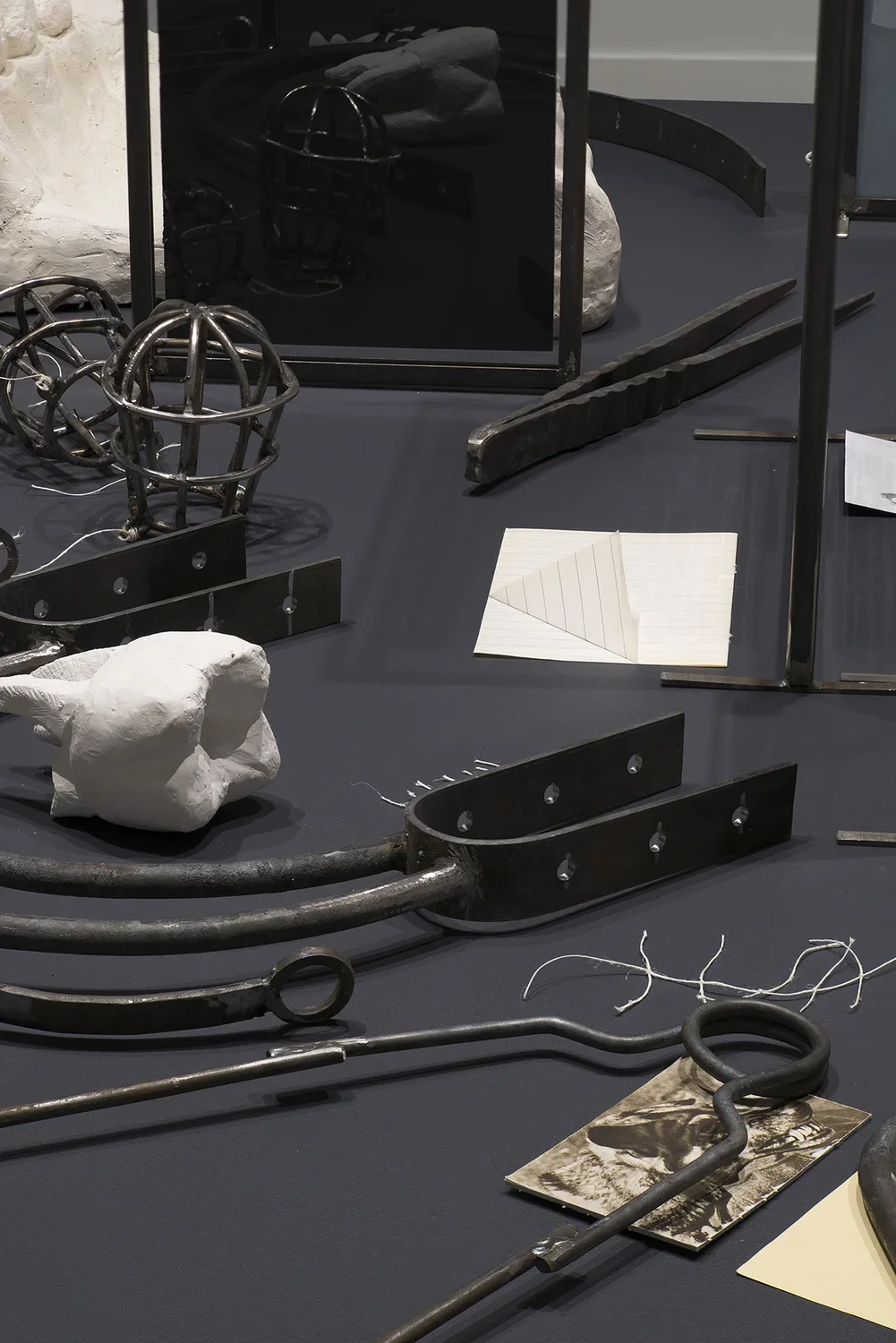 Collection of metal and plaster objects, including a cast of a tooth, as well as white string and glass picture frames.