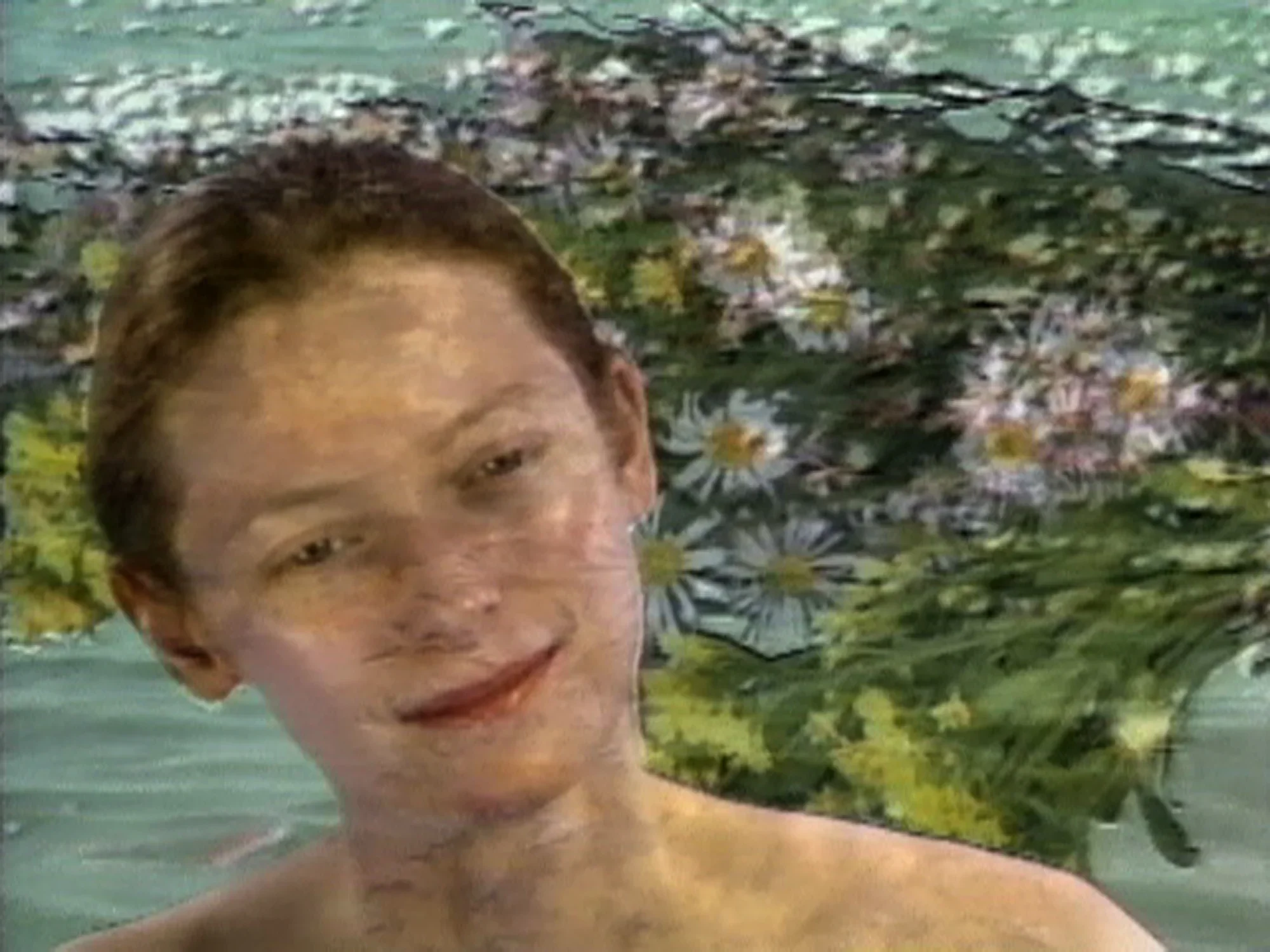 A woman with light skin and a slick pulled back bun appears from the next up without a shirt on. Overlayed is a pixelated image of daisy flowers. 