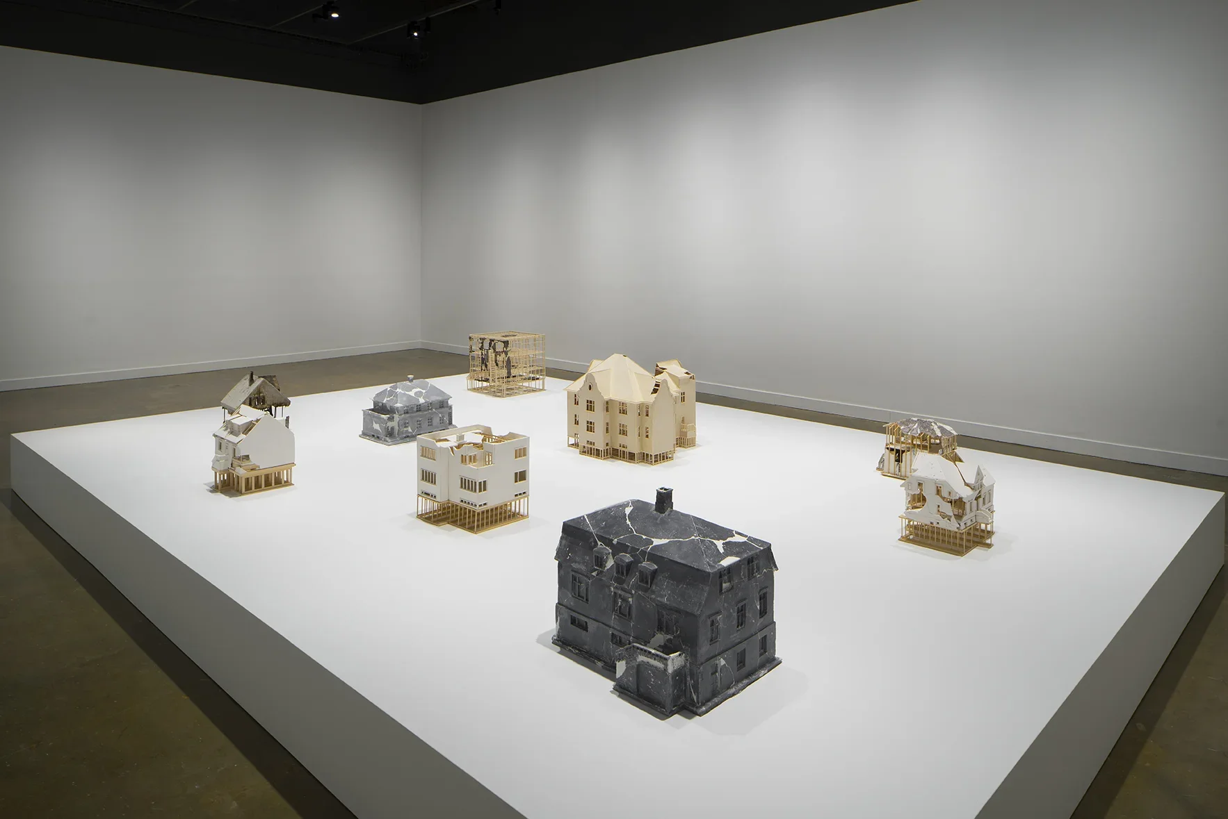 7 small sculptures of different homes on a large pedestal. 