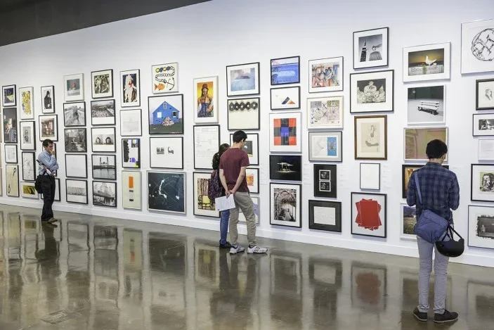 Students in gallery filled floor to ceiling with artworks.