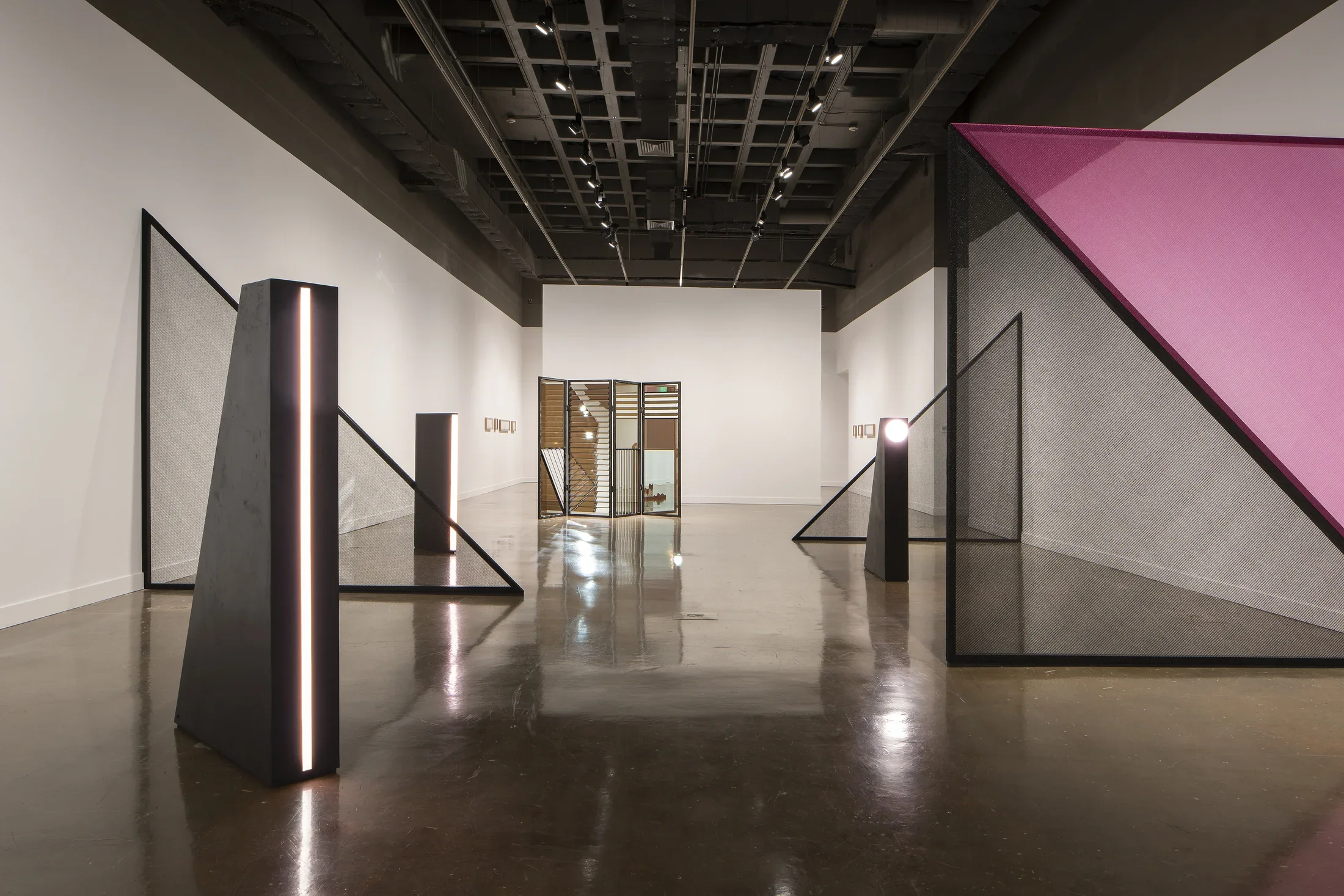 Three black light towers are interspersed with large net triangles. A mirrored louvered folding screen is in the rear.