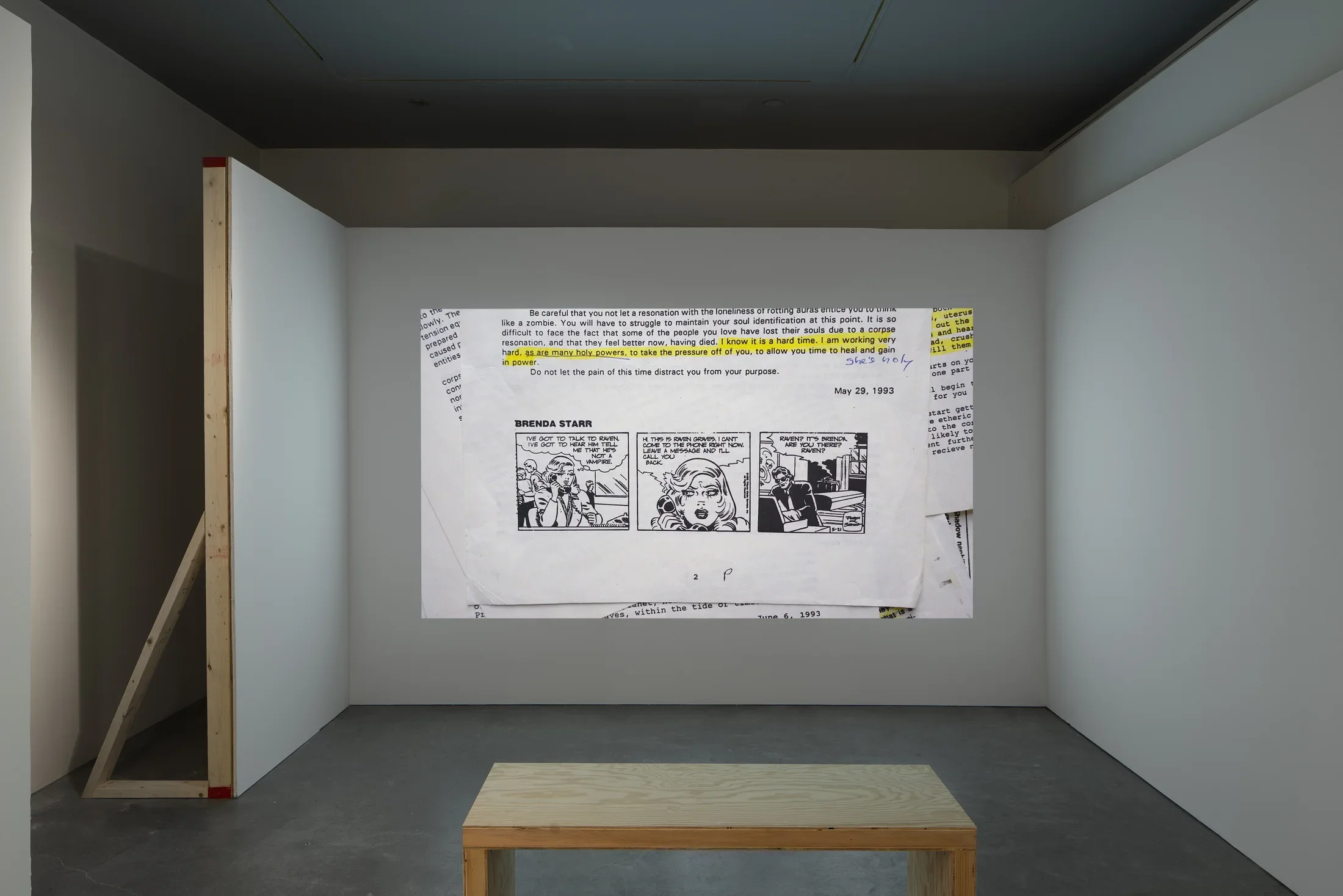 Still of papers, on top, a partial page with yellow-highlighted text above a black and white, 3-frame “Brenda Starr” cartoon