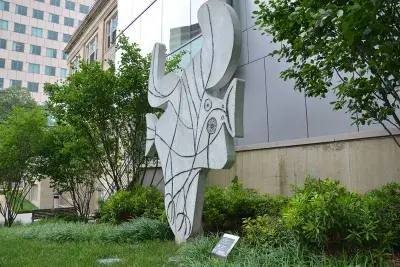 Concrete cut-out sculpture representing a bird with head and beak to the right, tail to the left, feet below, and spread wings above