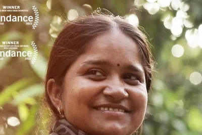 Image of a woman looking back towards the camera smiling with foliage behind her.
