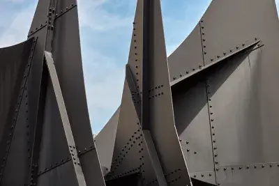 Detail of large steel sculpture with pointed edges. A blue sky is peeking through in the background.