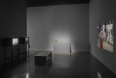 gallery at the MIT List Visual Arts Center includes two television sets, a bench, a vitrine, and a projection by Leslie Thornton.