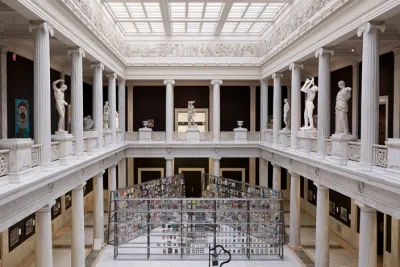 View inside two stories of a museum including columns and granite sculptures.