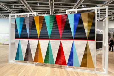 A large installation in a gallery featuring reflecting triangle shapes on a large canvas.