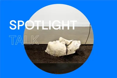 Blue background with the title &quot;Spotlight Talk&quot; in white and a circular image of a sculpture of a face in a box of brown mulch.