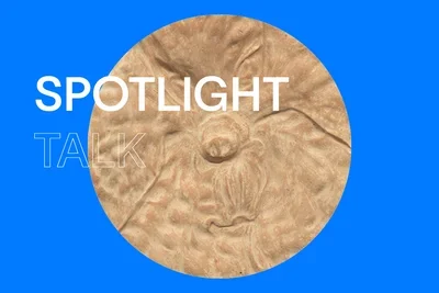 Blue background with white, uppercase letters that read "Spotlight Talk." In the center, there is a circular close up image of  a cream-colored relief sculpture, with a rough textured surface.