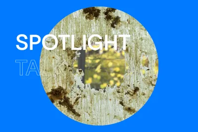 Blue background that reads &quot;Spotlight Talk&quot; in uppercase, bold white letters. There is a circular image of  a close-up of beeswax and dried flora smeared across the gallery window. A tree with yellow leaves is outside.