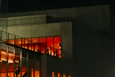: Through windows on the Brutalist façade of Renzo Piano-designed [building], visitors move through orange-hued galleries. Still from history as hypnosis