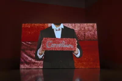 On a horizontal screen, a suited figure holds a glittering red box that reads “Carnelian.”
