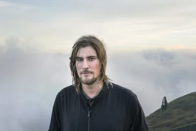 Portrait of artist Julian Charrière standing outside on a mountain.