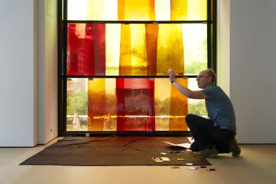 Portrait of artist Spencer Finch kneeling to work on a work of art.