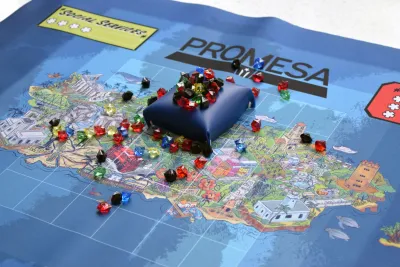 Image of board game 'Promesa' in progress. A collection of small black gems float atop a blue raft on top of a map.