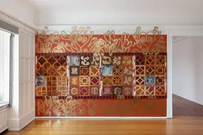 Red accent wall with geometric patterns that overflow onto the surrounding white walls and a light brown wood floor.