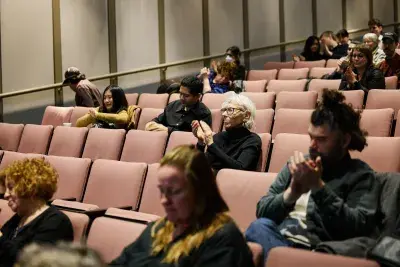 Crowd of people clapping and sitting in a theater audience.