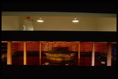 The gallery is split above and below. The top floor has a chair and two hanging lamps. The bottom is a warmly lit pond.