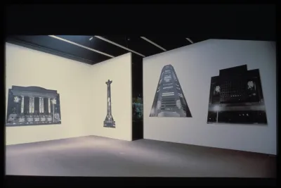 Four large cut-outs of black and white monuments hang adjacent on three walls.
