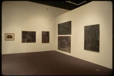 Six varyingly sized pastel sketches of human figures in muted greyscale color tones hang on adjacent gallery walls.