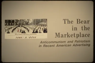 A wall of the exhibition with the title and advertisement for New Balance shoes stating, “Why runners make lousy communists.”