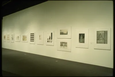 Architectural drawings line the walls of the gallery. Each one varies in size and orientation.