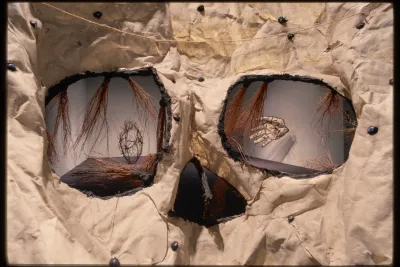 The eyes and nose of a skull show the installation of a heart and hand sculpture at the other end of the gallery.