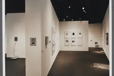Walls split the gallery into sections. Works line the walls in many configurations while others are shown on the floor.  