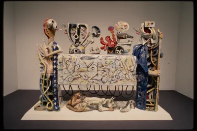 Abstracted figures around a table with an abstract expressionistic pattern. Figures represent people as well as animals. 