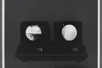 Two monitors sit side by side on a shelf. Each shows images within circular frames as if looking through binoculars.  